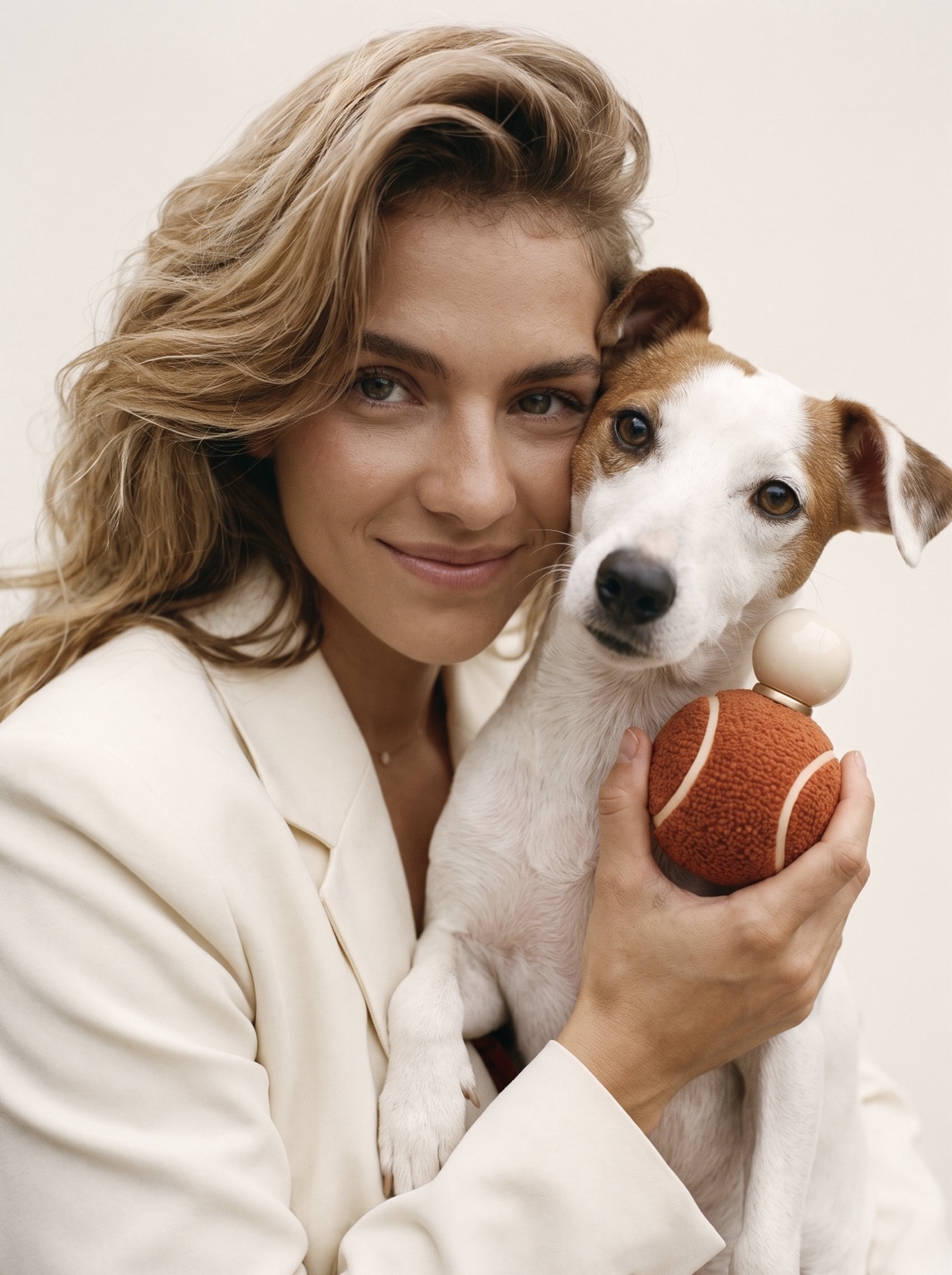 Woman holding a white and brown dog beside an orange bottle